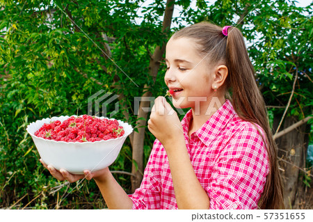 teen girl holding a bowl of raspberries in the 57351655