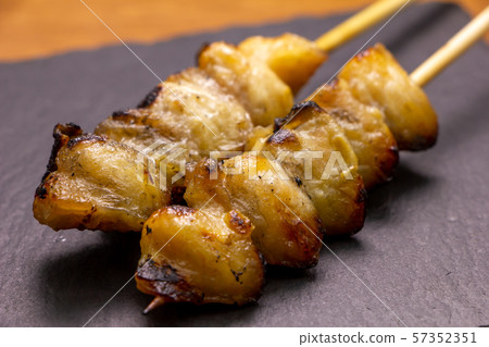 Yakitori and bonjiri skewers (salt grilled). Two on the slate plate. 57352351
