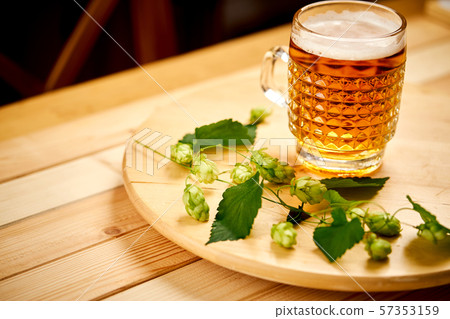 Large pint of beer with foam and sprigs of hops on wooden table Large pint of beer with foam and sprigs of hops on wooden table 57353159