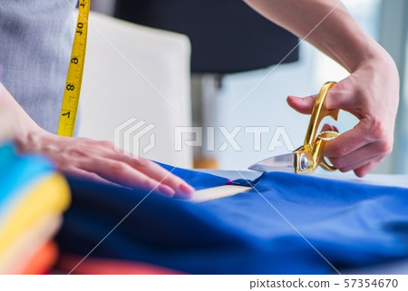 Woman tailor working on a clothing sewing stitching measuring fa Woman tailor working on a clothing sewing stitching measuring fa 57354670