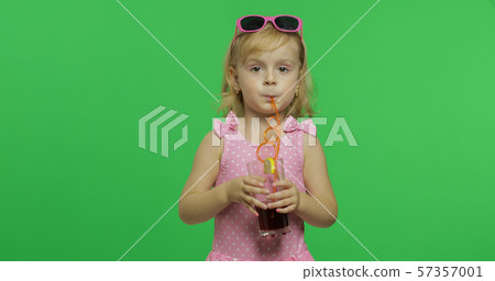 Child in pink swimsuit drinks juice cocktail with drinking straw. Chroma Key 57357001