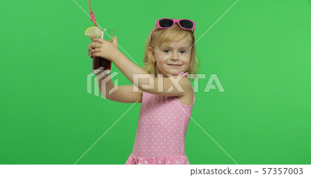 Child in pink swimsuit holds juice cocktail with drinking straw. Chroma Key 57357003
