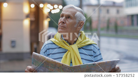 Senior male tourist exploring town with a map in hands and looking for the route Senior male tourist exploring town with a map in hands and looking for the route 57358252