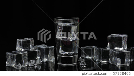 Shot of vodka with ice cubes against black background Shot of vodka with ice cubes against black background 57358405