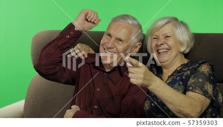 Senior aged man and woman sitting together on a sofa and watching TV. Chroma key 57359303