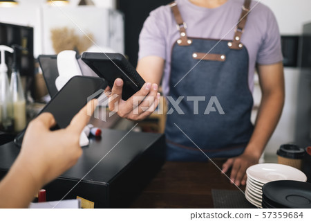 Customer doing contactless payment with phone in 57359684