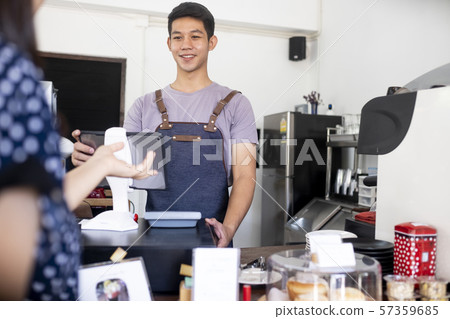 Young owner of coffee cafe service customer. Young owner of coffee cafe service customer. 57359685