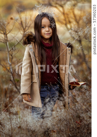 smiling little girl playing with autumn fallen leaves 57360203