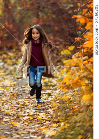 Happy adorable little girl runs in the autumn park. 57360205