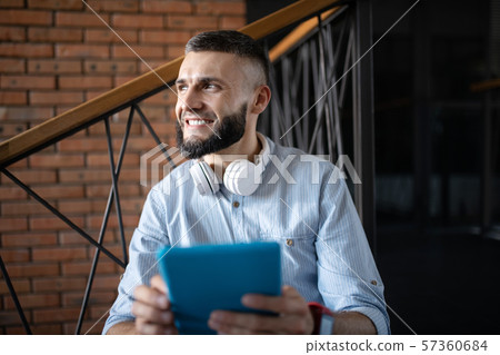 Smiling man holding little tablet while having little break 57360684