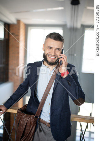 Smiling businessman speaking with colleague by the phone Smiling businessman speaking with colleague by the phone 57360888