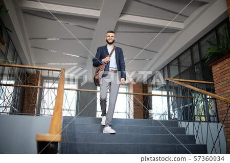 Excited smart trainee walking downstairs in the office Excited smart trainee walking downstairs in the office 57360934
