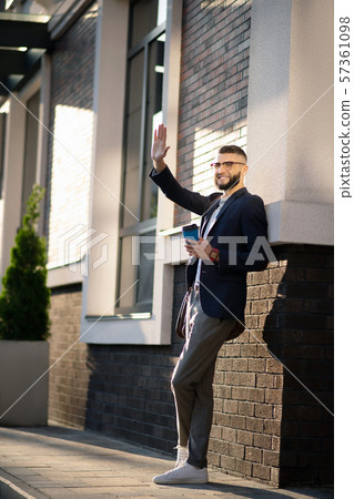 Office worker waving while meeting colleague in the street 57361098
