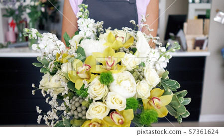 Florist woman comes with beautiful bouquet of roses and lilies in her hands. Florist woman comes with beautiful bouquet of roses and lilies in her hands. 57361624
