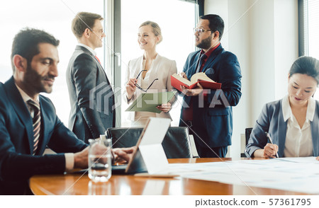 Turkish business man working on laptop with colleagues in background 57361795