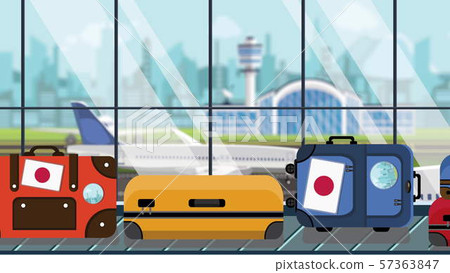 Baggage with Japanese flag stickers on carousel in airport, close-up. Travel to Japan related 57363847