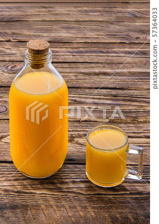 Fresh orange juice in bottle and mug on table Fresh orange juice in bottle and mug on table 57364033