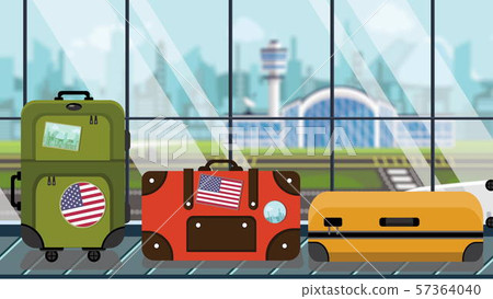 Luggage with American flag stickers on baggage carousel in airport, close-up. USA tourism related 57364040