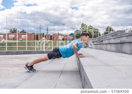 Athletic guy, in summer city push-ups from stairs, fitness workout, morning workout outdoors Athletic guy, in summer city push-ups from stairs, fitness workout, morning workout outdoors 57364500