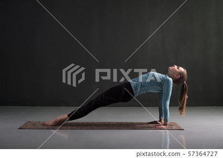 Woman practices yoga asana purvottanasana or upward facing plank 57364727