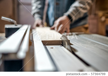 Man making wooden parts for furniture on thickness planer machine. 57364799