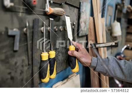 Caucasian man hand taking a chisel for wood working. Caucasian man hand taking a chisel for wood working. 57364812