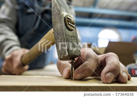 Carpenter hands with hammer and nail. Close up view 57364836