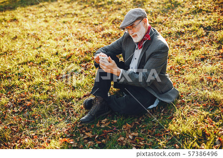Elegant old man in a sunny autumn park 57386496