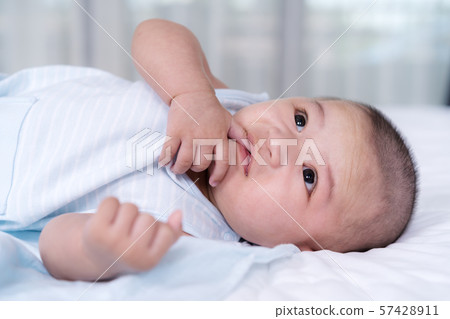 baby with finger in mouth on a bed baby with finger in mouth on a bed 57428911