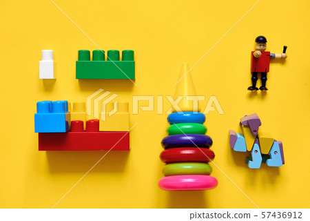 Flat lay of plastic and eco wooden toys. Developing games. Yellow background Flat lay of plastic and eco wooden toys. Developing games. Yellow background 57436912