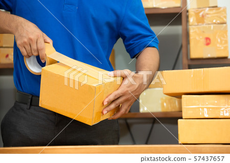 Worker courier man packing parcel box at office Worker courier man packing parcel box at office 57437657