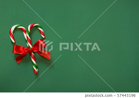 Two candy canes with red bow on green. Two candy canes with red bow on green. 57443196