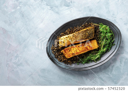Roasted salmon with sesame seeds, wakame and wild black rice, top shot with a place for text 57452320