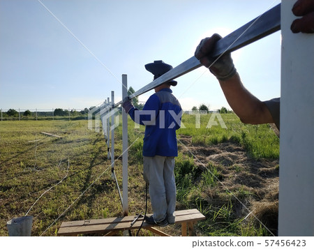 Worker in protective mask welds steel handrails 57456423
