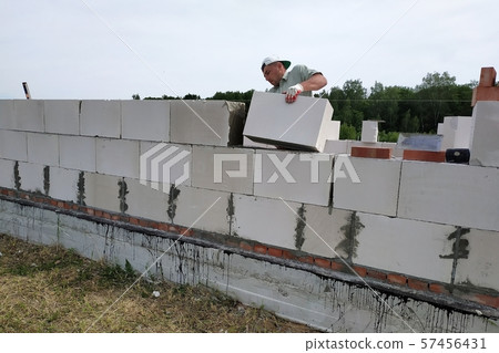 A construction site worker puts a block on the 57456431