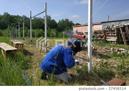 A fence installer welds a metal profile to a new 57456514
