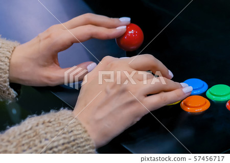 Woman gamer playing retro arcade machine game and pushing bright buttons 57456717