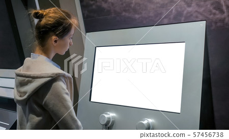Woman looking at blank white display kiosk at exhibition - white screen concept Woman looking at blank white display kiosk at exhibition - white screen concept 57456738