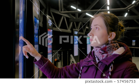 Woman using interactive touchscreen display of electronic multimedia kiosk Woman using interactive touchscreen display of electronic multimedia kiosk 57456753