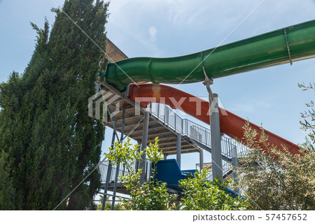 Aqua park. Green, red and blue water slide. Blue sky with green trees. Aqua park. Green, red and blue water slide. Blue sky with green trees. 57457652