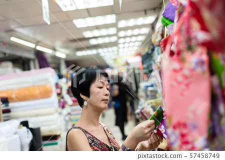 woman pick a roll of cloth at the fabric mall 57458749