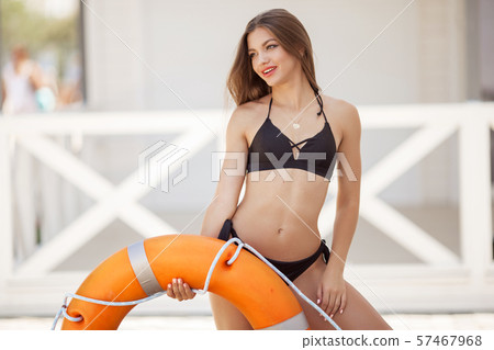 Beautiful young slim girl with perfect body is holding yellow lifebouy on the beach 57467968