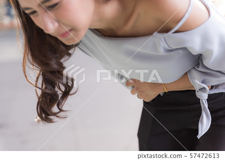 Young asian woman suffering pain on stomach while 57472613