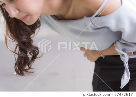 Young asian woman suffering pain on stomach while 57472617