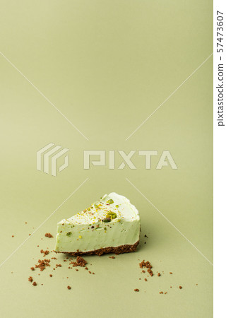 One slice of pistachio cheesecake on sight green background 57473607