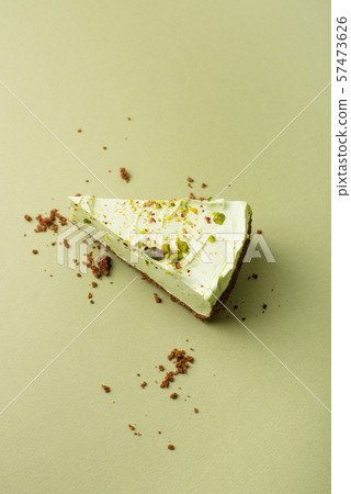 One slice of pistachio cheesecake on sight green background 57473626