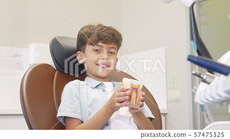 Cute young boy smiling to the camera, holding tooth model Cute young boy smiling to the camera, holding tooth model 57475325