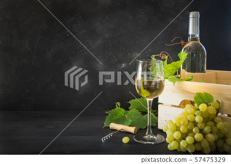 Bottle of white wine with wineglass, ripe grape on black wooden table. Bottle of white wine with wineglass, ripe grape on black wooden table. 57475329