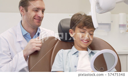 Mature male dentist working with charming young boy Mature male dentist working with charming young boy 57475348