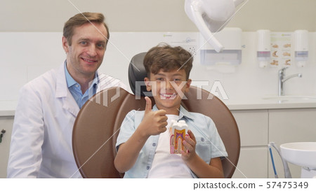 Happy little boy showing thumbs up after successful dental checkup with dentist Happy little boy showing thumbs up after successful dental checkup with dentist 57475349